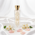 Flacon de parfum nacré aux accents dorés gravés d'arabesques, posé sur soie blanche avec jasmin et pétales de rose